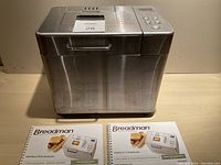Front view of stainless steel Breadman bread maker machine with two instruction manuals in front.