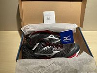 Pair of black Mizuno running shoes inside an open box with white tissue paper, accompanied by a Mizuno instruction booklet.