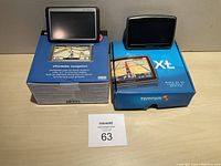 Garmin Nuvi 250W and TomTom XL350 GPS units sitting on top of their original retail boxes, front view showing screens and packaging.