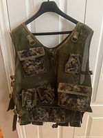 Front view of the XL paintball tactical vest showing multiple camouflage pockets and Velcro straps.