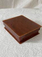 Closed view of rectangular brown Bakelite box sitting on neutral fabric background.