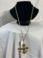 Full view of gold-tone link chain necklace displayed on a black bust, showing the chain length and cross pendant.