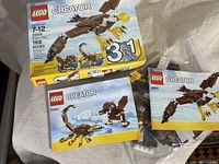 Photo shows Lego Creator 3-in-1 set 31004 box, two instruction manuals featuring different build options, and a zip lock bag with Lego pieces.