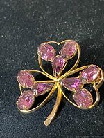 Front view of the gold plated shamrock brooch with purple amethyst stones, showing the detailed prong settings and stone cuts.