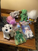 Full view of mixed TY Beanie Babies and assorted plush toys arranged on a wooden surface showing two boxed bears and several unboxed plush.