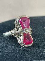 Front view showing two hourglass-shaped pink stones with gold filigree setting and central small round feature, ring size stamped inside band.