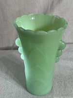 Front view of the green translucent Fire King vase with scalloped rim and bubble side detail.