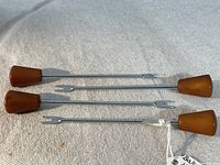 Four vintage cocktail forks laid out showing Bakelite handles and stainless steel prongs