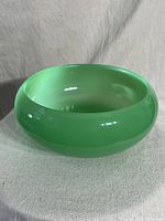 Top-angle showing smooth green jadeite glass with rolled inward cuffed rim.