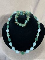 Full view of vintage glass and malachite bracelet and necklace displayed on black stand.