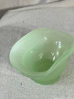 Top-down close-up of pale green jadeite mini candy bowl showing interior and irregular wave edge