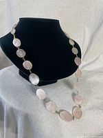 Full view of vintage pink stone necklace displayed on black bust with circular pink stones linked and two clasps visible.