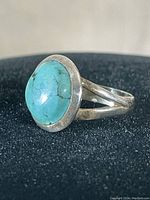 Close-up lateral view of vintage sterling silver ring with turquoise stone showing profile and band split.