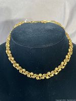 Full view of the gold plated floral linked necklace on a black display bust.