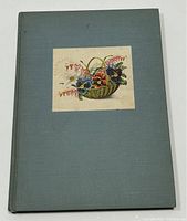 Front cover of the hardcover book with light blue cloth and a color illustration of garden flowers in a basket.