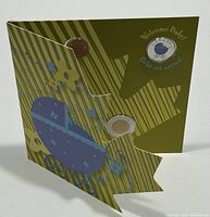 Closed packaging for the 2010 Canada Welcome Baby 7 Coin Set with green card and baby carriage illustration