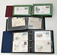 Three binders open displaying a variety of world first day covers and postal covers in protective sleeves.
