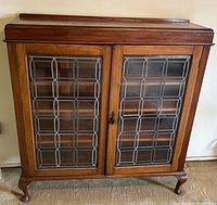 Front view of bookcase showing double leaded glass doors, top molding and cabriole feet