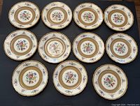 Overview of all 11 dinner plates showing floral, gold and brown decorative design with scalloped edges.