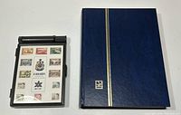 Blue plastic commemorative stamp box with 1967 Canada Centennial thematic stamp sheet next to matching blue binder album