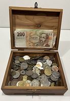 Top view of cedar box open showing vintage coins and banknotes inside.