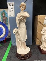 Full view of porcelain nurse figurine standing with bouquet