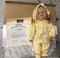 One unopened Baby Yellow Sunshine porcelain doll with visible Certificate of Authenticity and original tissue paper inside an open box.