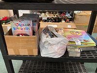 Wide shot of collectibles on black shelving including boxed TY Gear for Beanie Kids outfits, plastic bag with items, and stacked collector cards.