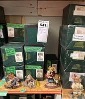 Four Boyds Bears collectible figurines displayed with original boxes stacked behind. Labels on boxes read 'Poor Ol Bear', 'Scardy Cat', and 'Princess Readalot'. Figurines include teddy bears seated and standing, dressed in clothing matching their character.