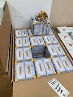 Boxed sets of Cherished Teddies figurines arranged in a cardboard container showing the blue trunk-themed boxes stacked.