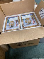 Open cardboard box containing two Cherished Teddies Tug A Heart decorative gift tins sealed in plastic wrapping.