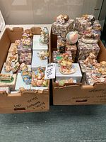 Boxed Cherished Teddies figurines arranged in two cardboard boxes showing various individual items with original boxes beneath.