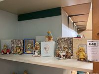 Shelf view showing multiple Cherished Teddies figurines, some with original boxes, arranged closely together.