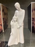 Porcelain figurine of a father and daughter holding hands, glossy white finish, showing full figure and details of dress and hair braids.