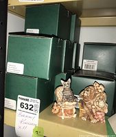 Multiple Harmony Kingdom figurines displayed with original green boxes stacked behind them on a shelf