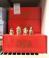 Four detailed, Christmas-themed Harmony Kingdom ornaments displayed in front of stacked original red boxes labeled 'Harmony Kingdom'