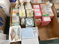 Box containing multiple Precious Moments figurines with several boxes stacked and some figurines visible outside the boxes.