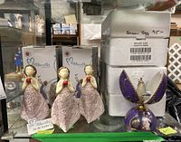 Four More Than Words figurines holding red roses with boxes in the background, and one purple Queen Elizabeth musical egg closed.