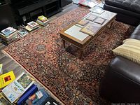Area rug under coffee table with visible intricate floral and geometric patterns and fringed edges showing wear.
