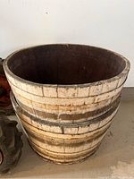 Front view of one wooden half-barrel showing exterior, metal bands, and base, with noticeable wear and peeling paint.