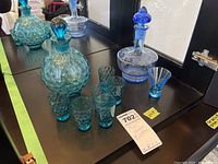 Photo of two decanters and six liqueur glasses on black surface.