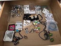 Full drawer view showing assorted costume jewelry including rings, earrings on cards, brooches, and necklaces.