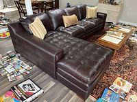 Frontal view of three-piece tufted brown leather sectional with chaise and three throw cushions