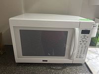 Front view of white Kenmore Elite microwave oven showing door, handle, and control panel with buttons and display.