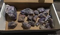 Box containing 15 rough amethyst rocks of various sizes ranging from 2 to 5 inches tall in a cardboard box.