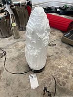 Full view of the tall white crystalline selenite salt lamp on black stone base viewed from side