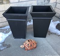 Full lot showing two black steel tapered planters and a cast iron turtle yard decoration with rust on concrete surface outdoors.