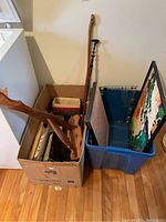 Photo showing boxes containing wooden furniture parts, walking sticks, framed boards, and a woven basket.