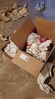 Box partially opened showing wrapped china pieces inside and packing materials scattered outside the box.