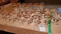 Full view of assorted stemware showing various sizes and types with gold rims on wooden surface